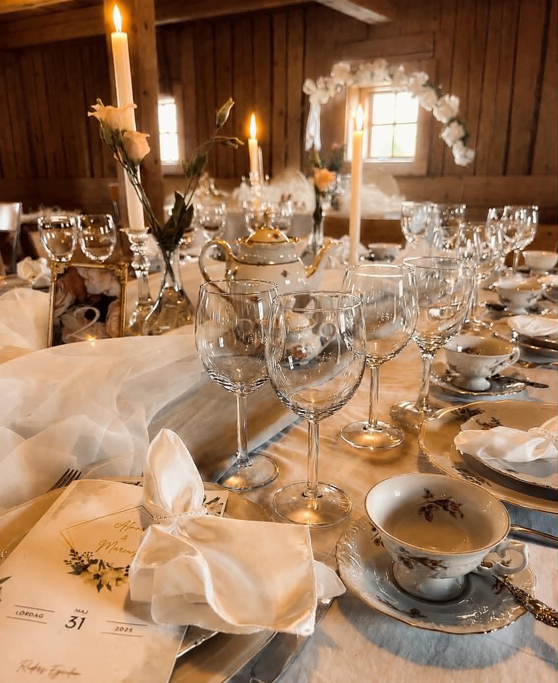 Ljus och stämningsfull bröllopsdukning med vintageporslin, levande ljus och glas